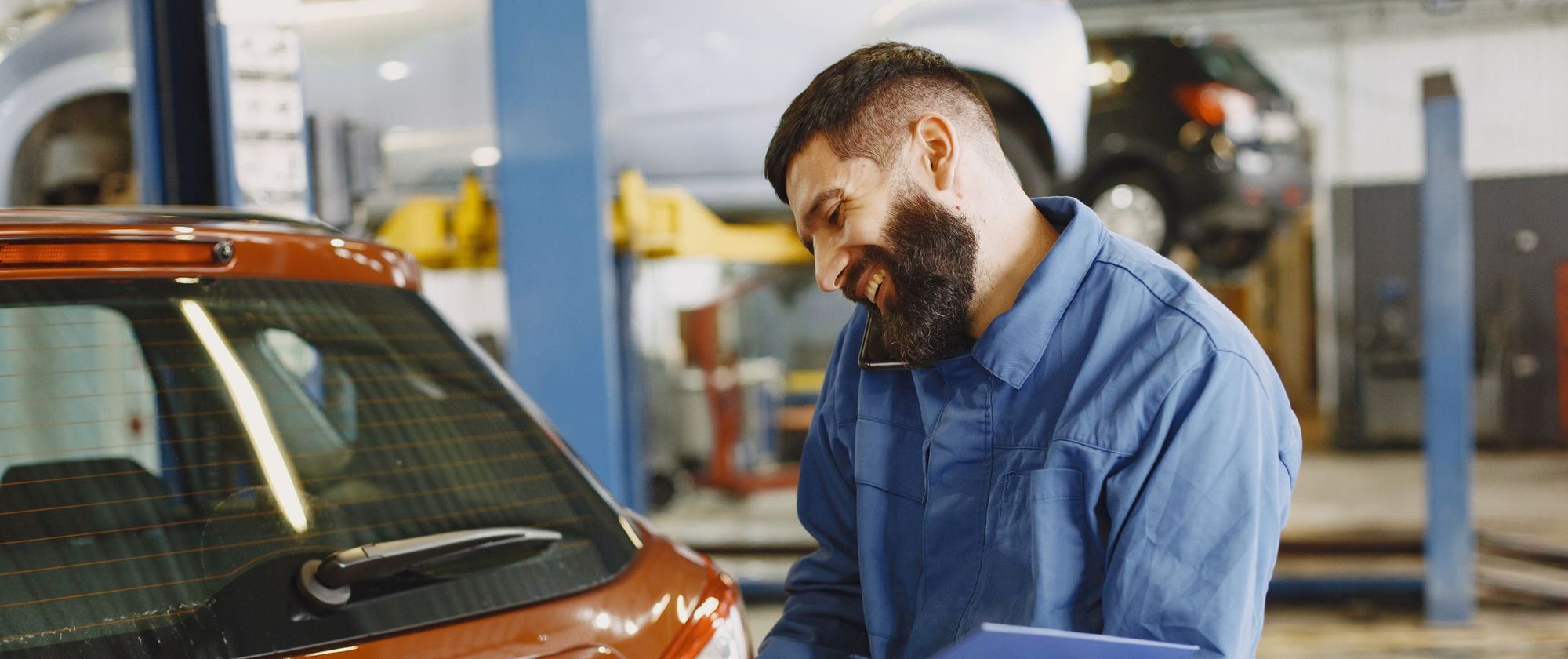 Mechanic reviewing repair paperwork beside a car in a service bay